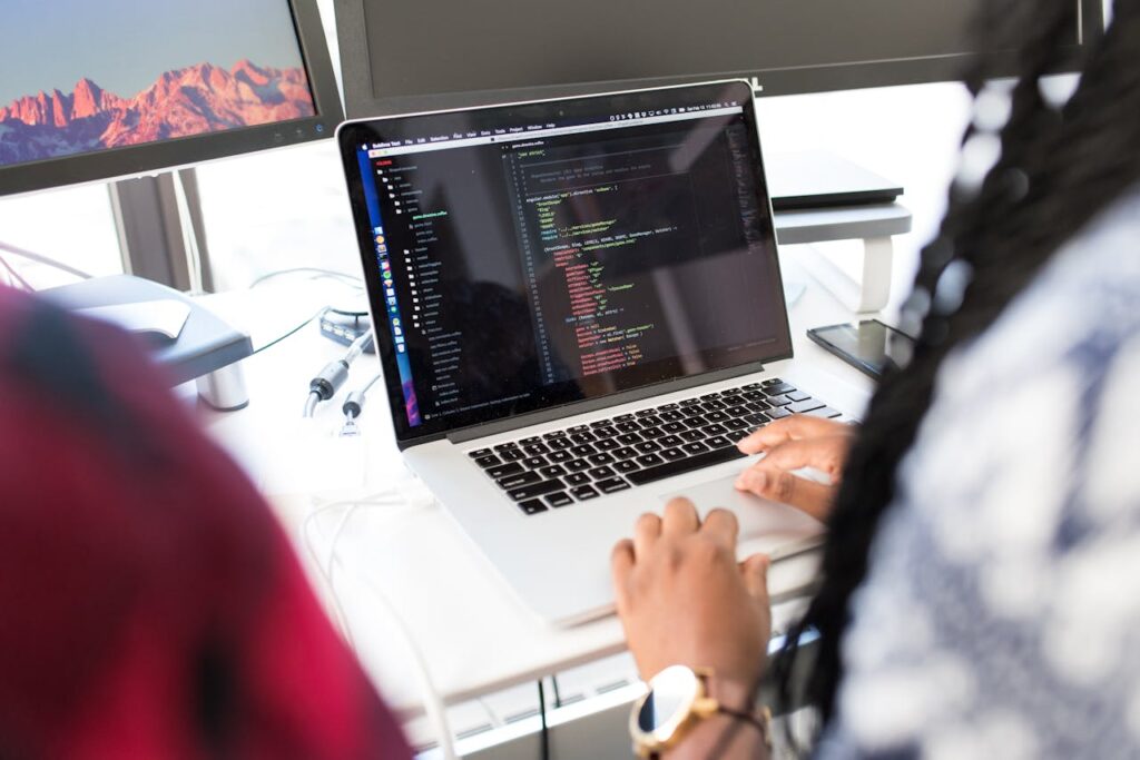 pexels photo 1181467 A woman coding on a laptop in a modern office environment with multiple monitors.